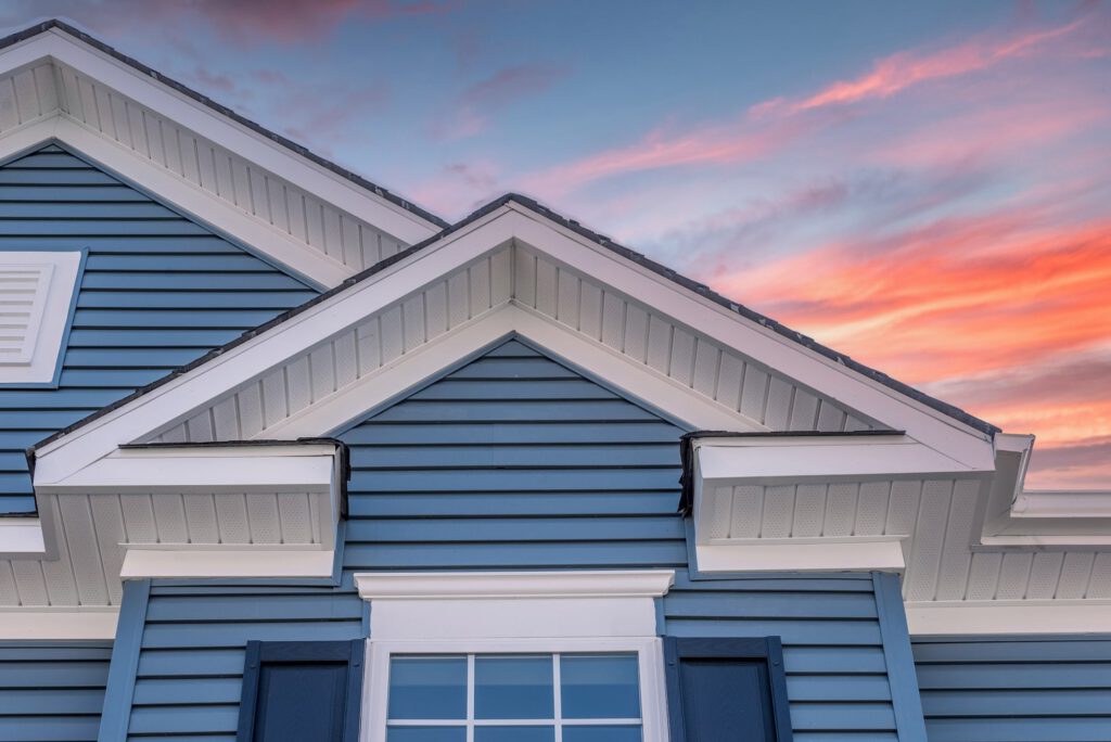 Blue house roof under colorful sunset sky.