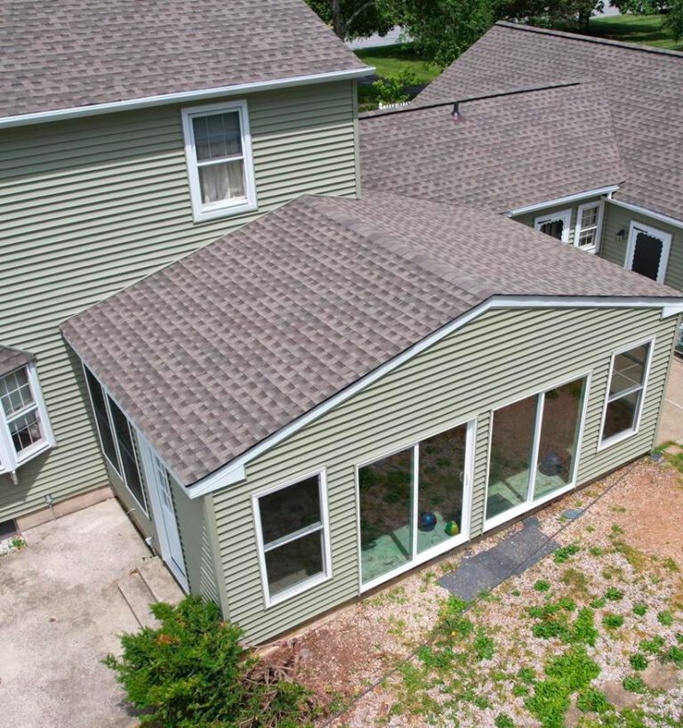 Aerial view of house with green siding and patio.