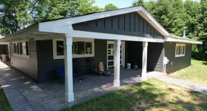 Modern single-story house with dark siding and porch.