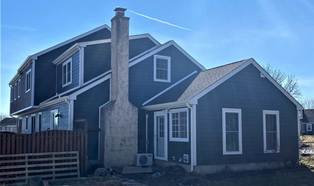 Blue two-story house with chimney in sunlight.