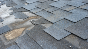 Damaged roof shingles in need of urgent repair.